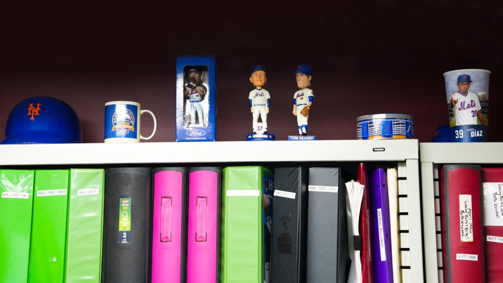 A row of Mets mementos above a bookshelf