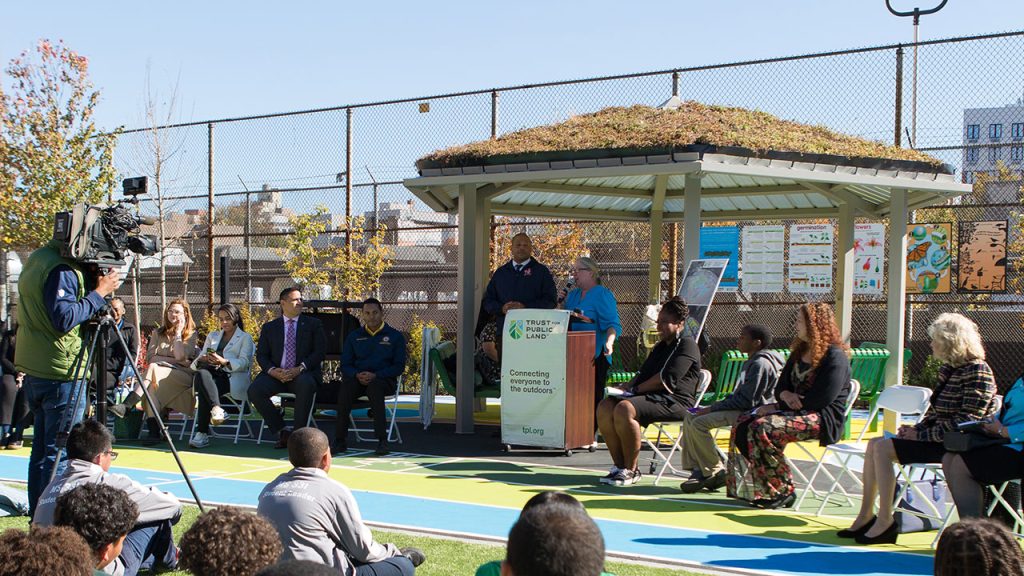 A woman speaks to a CROWD from under a gazebo