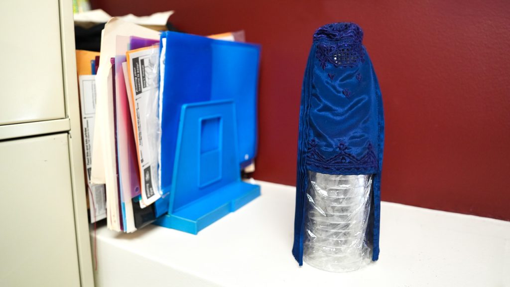 A mini burqa for a Barbie rests atop a stack of plastic cups.