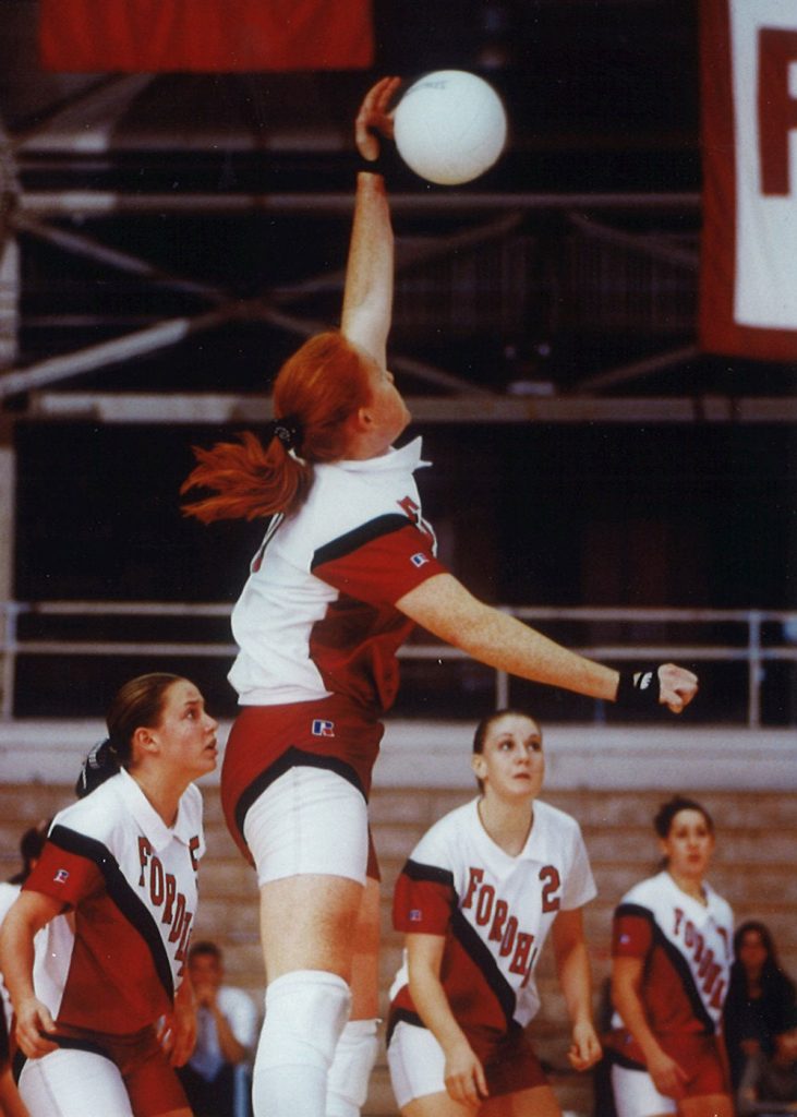 Fordham volleyball player Cindy Vojtech leaps in the air to hit the ball as her teammates look on