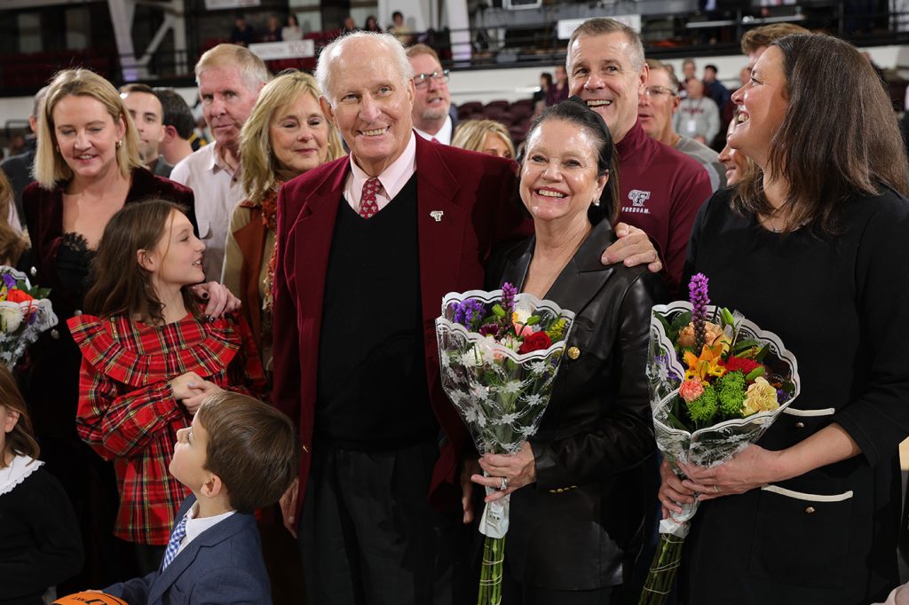 Fordham grad and former longtime athletic director Frank McLaughlin, his wife, and members of their family are all smiles at center court in the Rose Hill Gym