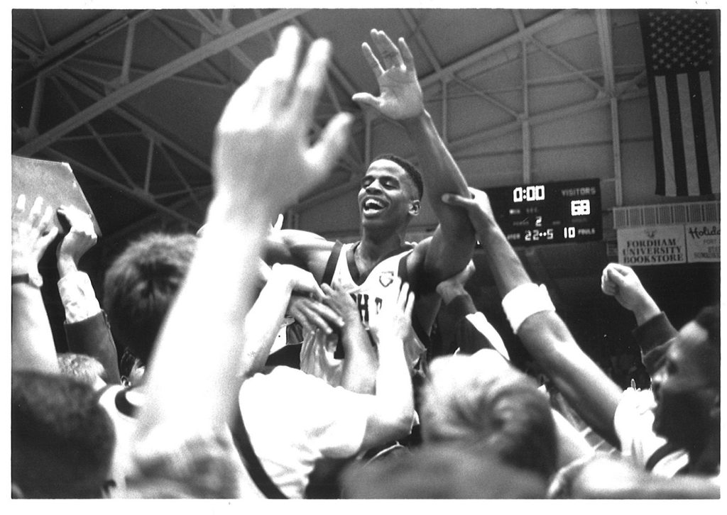 Fordham men's basketball player Jean Prioleau is lifted in the air by his teammates after hitting a game-winning shot