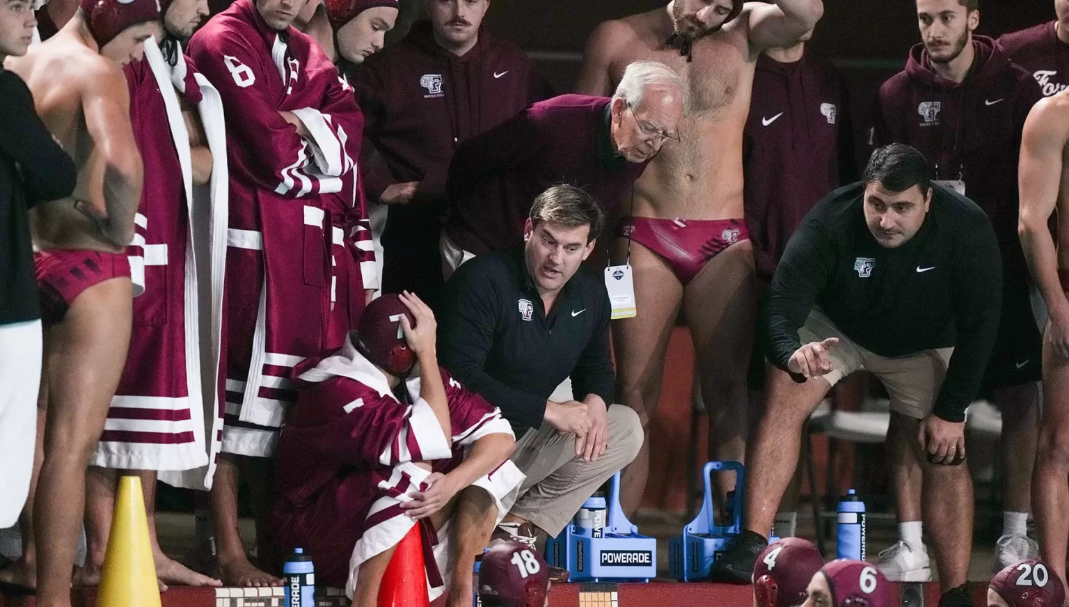 Water polo team and coach in conversation outside the court