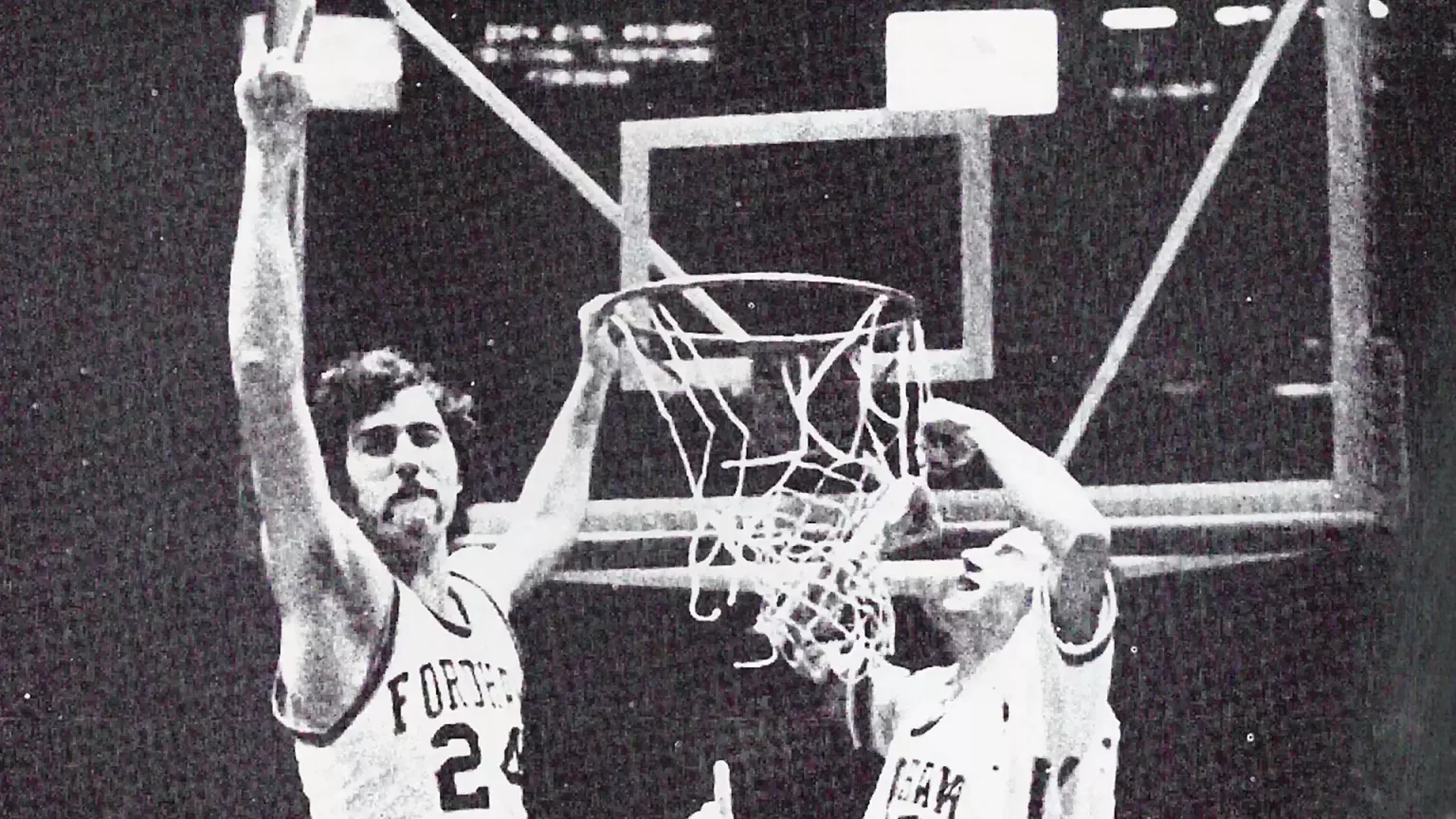 Black and white photo of Fordham basketball player on hoop.